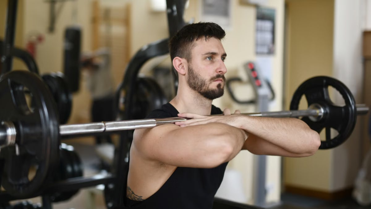 A focused man lifting weights indoors showcasing strength and concentration.